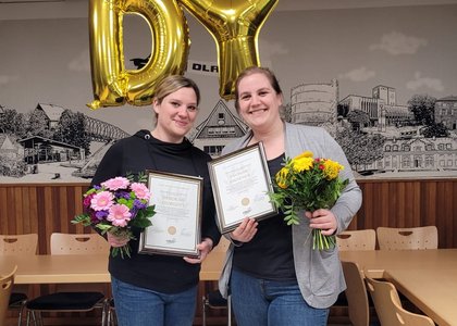Ein Bild von den ehemaligen Mitgliedern des Jugendausschuss Deborah Murgott und Yvonne Riesener, die jeweils ihre Urkunde und einen Blumenstrauß halten und lächeln